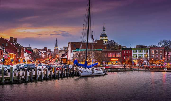 Annapolis harbor at sunset with the illuminated capitol building in the background